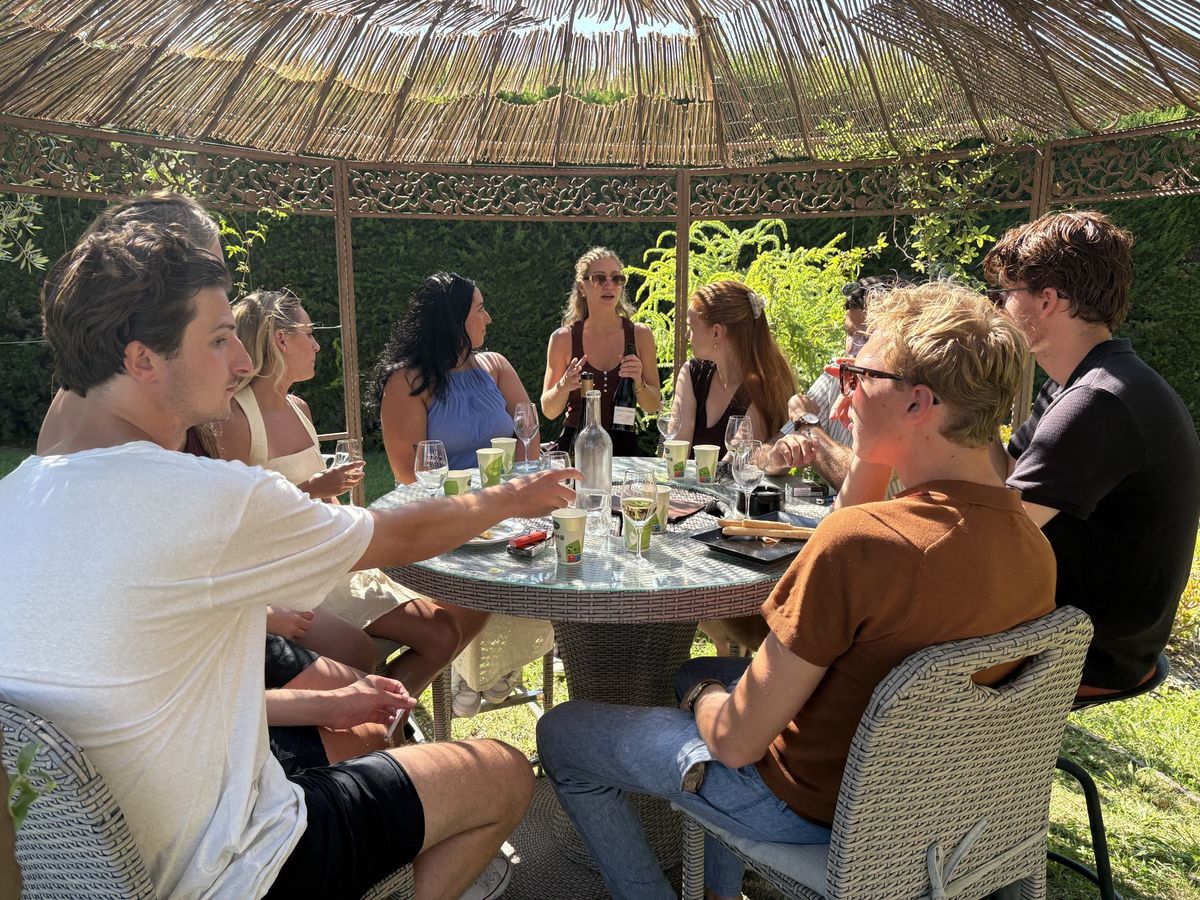 Groupe d'invités autour de la table de dégustation sous la tonnelle