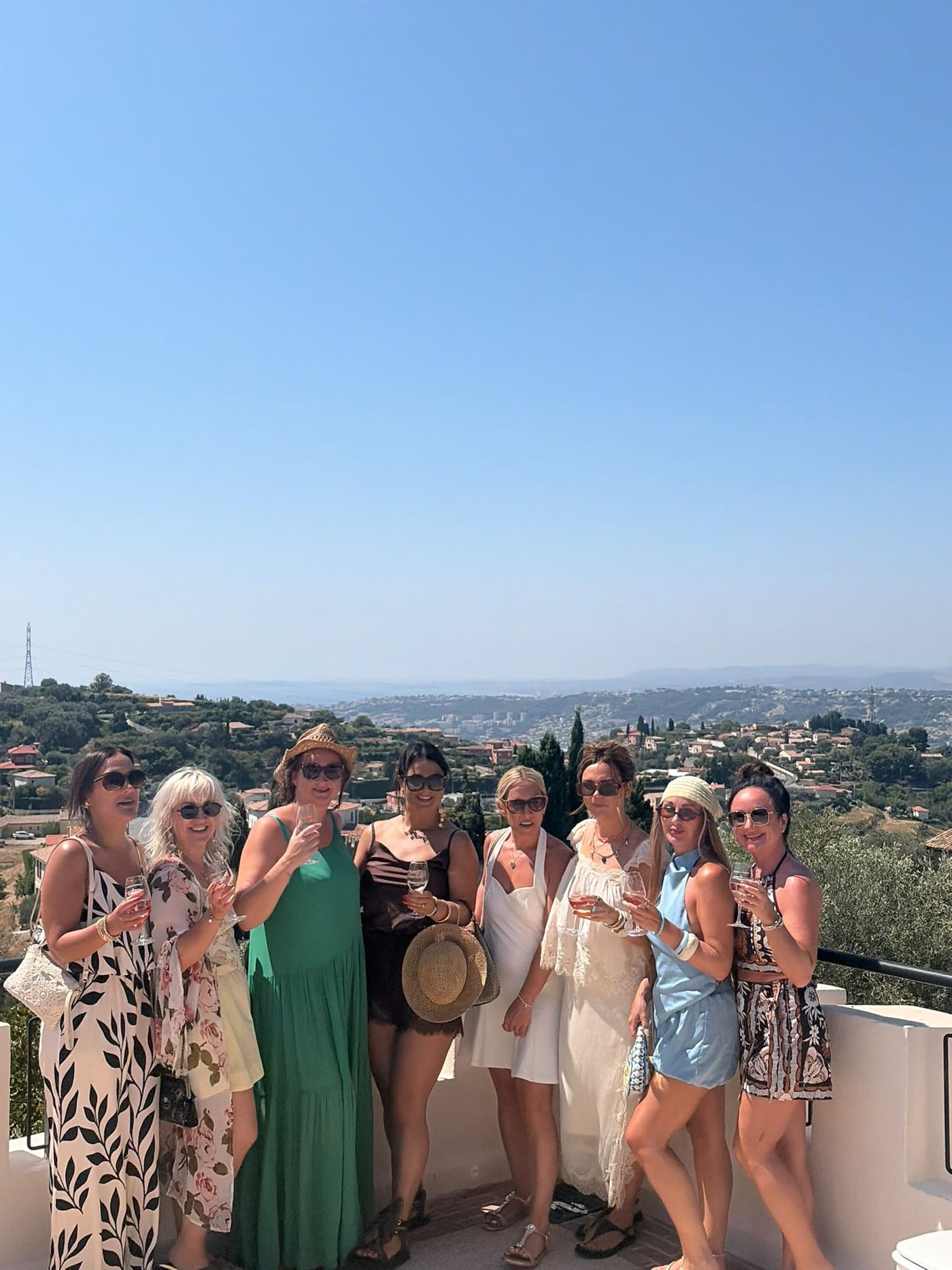 Groupe d'invitées trinquant sur une terrasse panoramique au-dessus de l'arrière-pays niçois